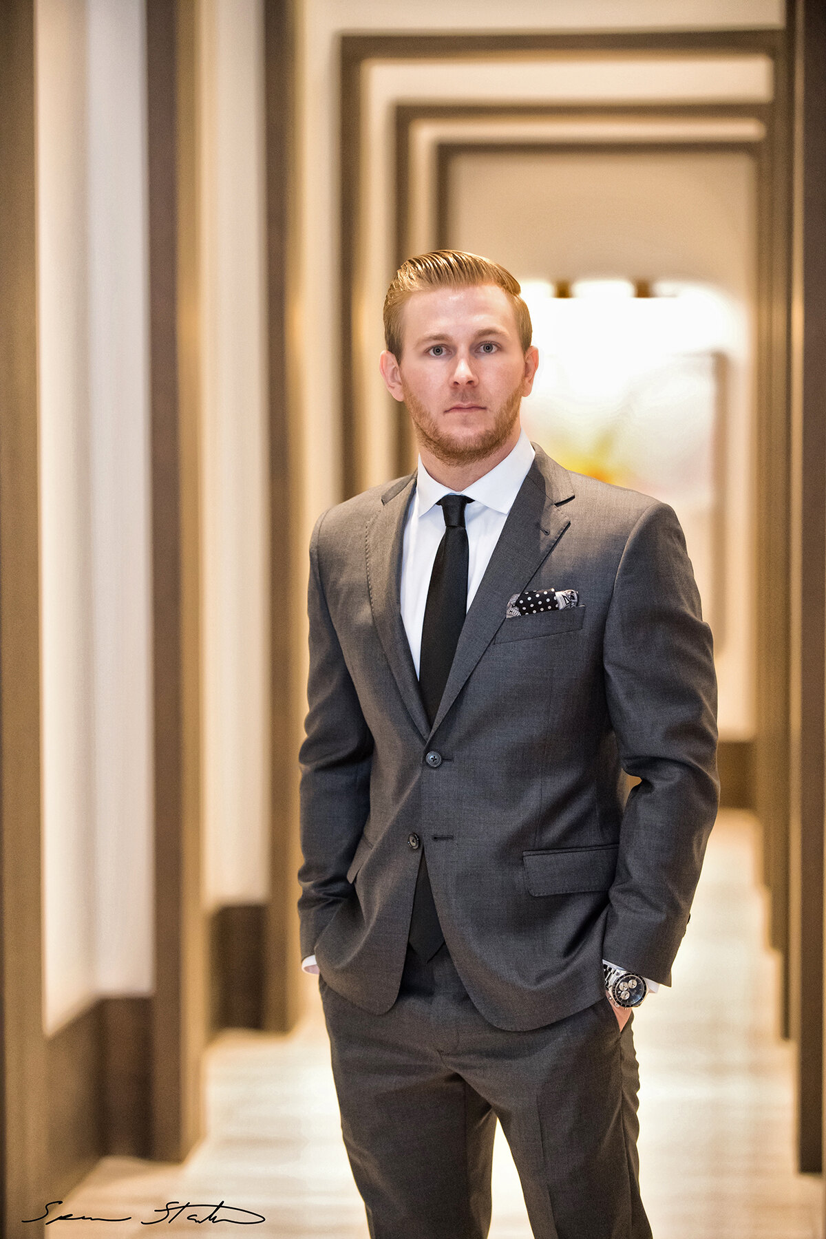 Entrepreneur Ryan White, founder of Social Revelation, in a gray suit with hands in pockets in a long hallway